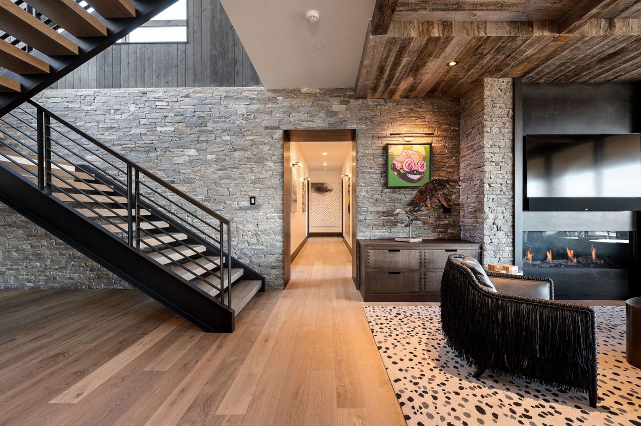 Stone-wall stairwell and hallway gallery with cantilevered black steel staircase &mdash; Wasatch Back home by Techi
