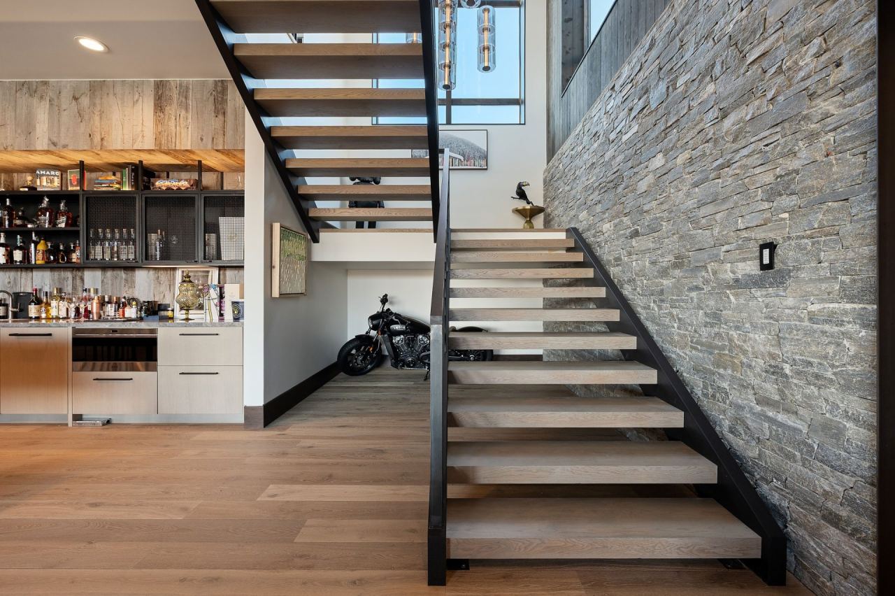 The Colony stone-clad cantilevered staircase under a 24-foot ceiling