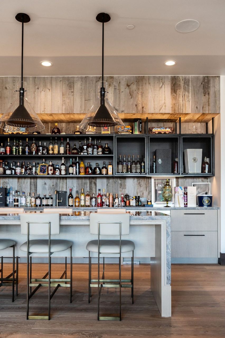 Home bar with stacked-bottle wall and warm pendants &mdash; Park City home by Techi